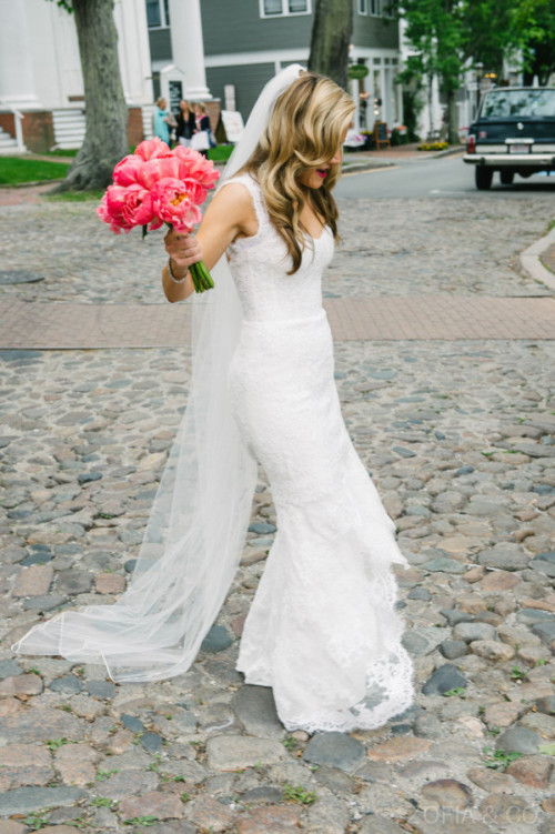 A Nantucket bride carries a bouquet of coral pink peonies on Main Street.