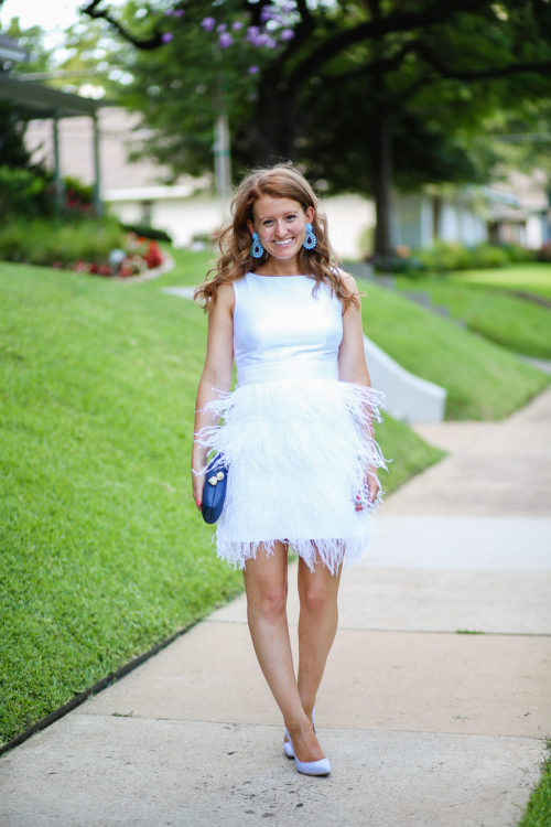 design darling wears a white feather dress by sail to sable