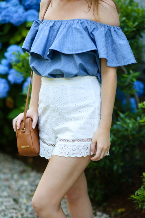 chambray off the shoulder top with tan crossbody bag and white eyelet shorts on design darling